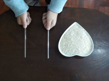 Cropped hand holding chopsticks with food on table