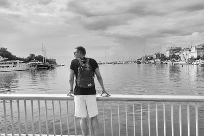 Full length of man standing on railing against sky