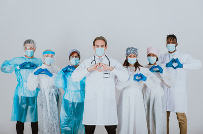 Portrait of doctors wearing mask standing against white background