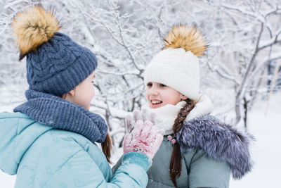 Two smiling girls in warm clothes met in a snowy park. winter walks, lifestyle