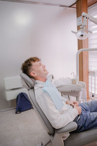 Teenager with curly hair sits in a chair at the dentist at the reception