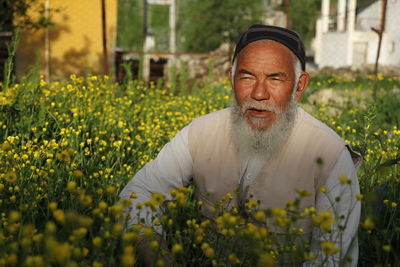 Portrait of young man with yellow flowers in field