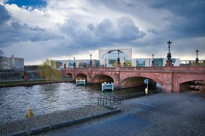 Bridge over river in city against sky