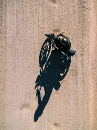 From above aerial view of person driving motorbike on rural road in sunlight in countryside