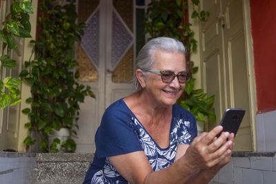 Portrait of smiling woman using mobile phone outdoors