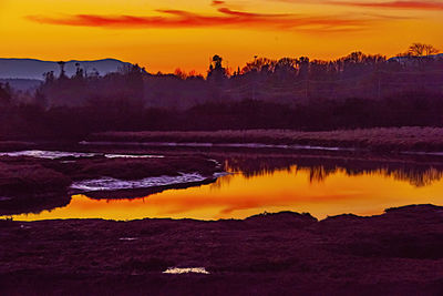 Scenic view of lake against orange sky