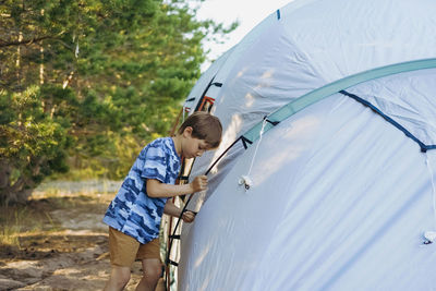 Cute little caucasian boy helping to put up a tent. family camping concept