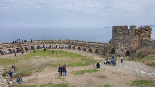 People at historical building against sky