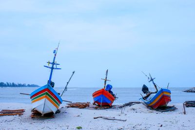 Deck chairs on beach against sky during winter