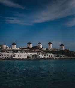 Sea by buildings against blue sky