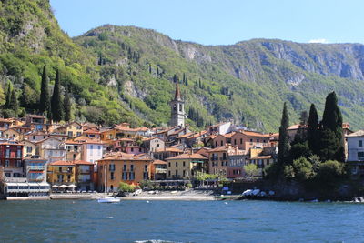 Houses by river and mountains against clear sky