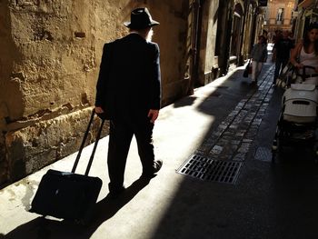 Rear view of man with luggage walking in pathway