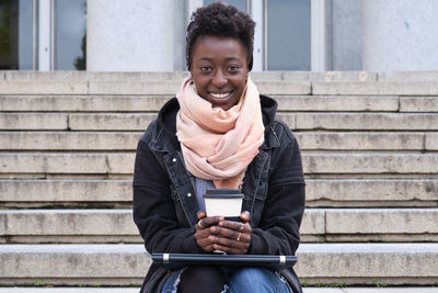 Portrait of smiling young woman sitting on staircase