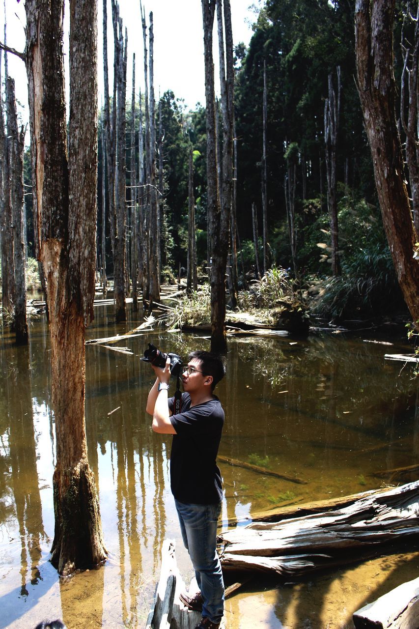 tree, water, lifestyles, rear view, winter, leisure activity, cold temperature, men, forest, tree trunk, season, snow, lake, full length, reflection, nature, walking, standing