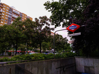 Road sign by trees in city