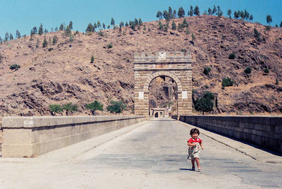 Cute girl running on footpath during sunny day