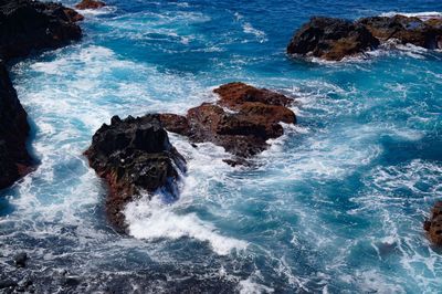 High angle view of waves splashing and crashing  on and over rocks white water surf 