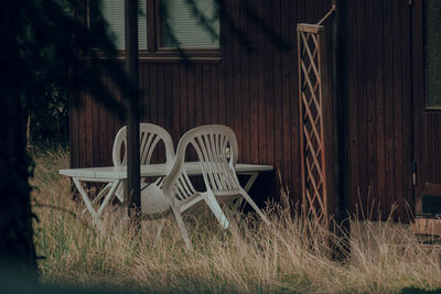 Empty chairs on field against building