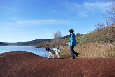 Woman and dog walking at a lakeshore in winter sunlight