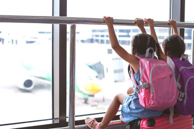 Rear view of siblings sitting at airport