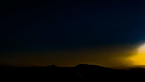 Scenic view of silhouette mountain against sky at sunset