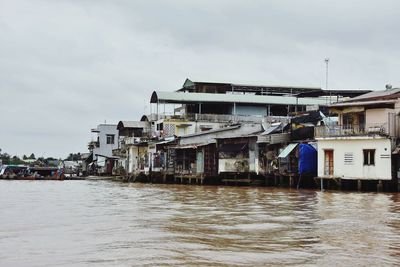 Houses by sea against sky in city
