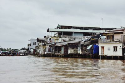 Houses by sea against sky in city