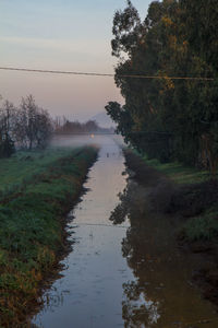 Scenic view of canal amidst trees against sky