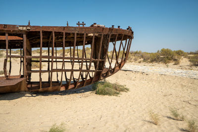 Damaged boat on beach against clear sky