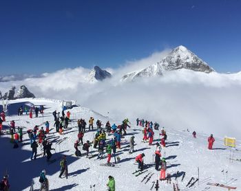 People skiing on snowy field against clear sky