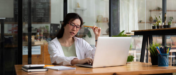 Young woman using phone while sitting on table