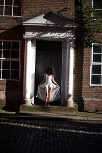 Full length of woman sitting on window of building