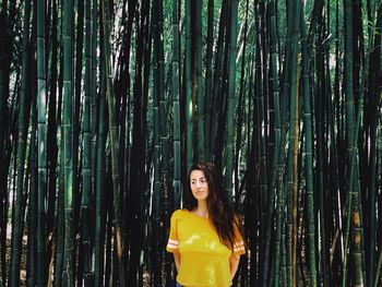 Thoughtful young woman standing against bamboo