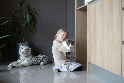 Cute girl playing with cat playing at home