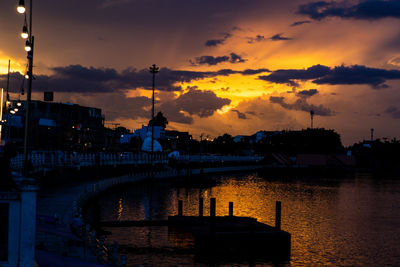 Silhouette bridge over river against sky during sunset