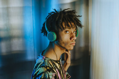 Thoughtful man listening music through wired headphones