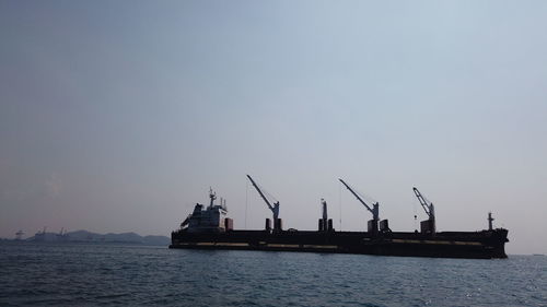 Commercial dock by sea against clear sky