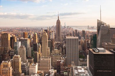 Aerial view of buildings in city against cloudy sky