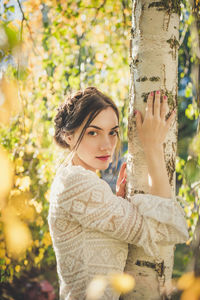 Beautiful young woman in a white lace blouse under the birch tree in park. summer time