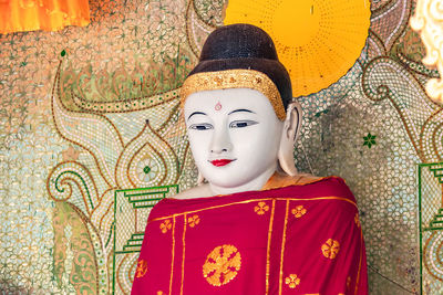 Close-up of a buddha statue with a red robe  inside the shwedagon pagoda in yagon, myanmar