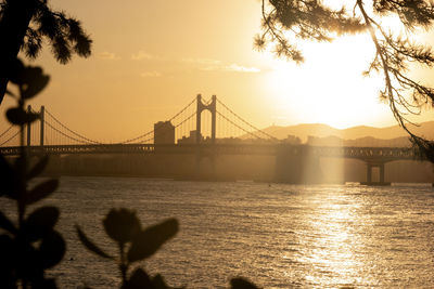 Silhouette bridge over the sea against sky during sunset