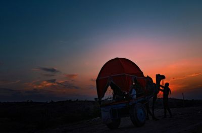 People standing on land against sky during sunset