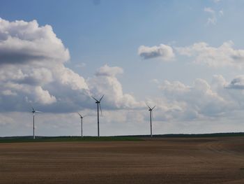 Windmills on field against sky