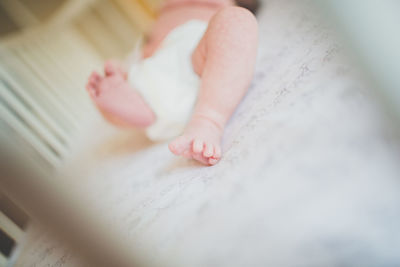 Low section of baby feet on bed at home