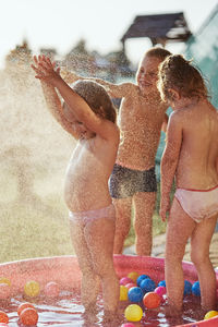 Cheerful siblings enjoying while standing in wading pool at yard