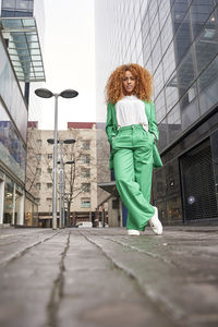 Businesswoman with hands in pockets standing on footpath