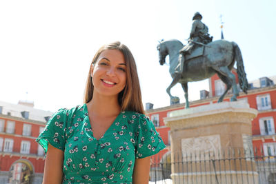 Portrait of a smiling young woman statue against built structure