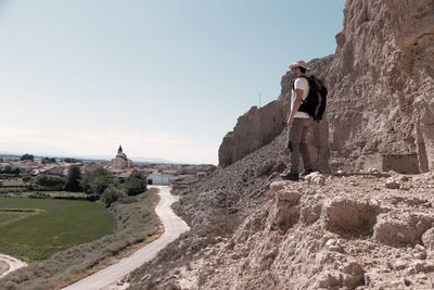 Rear view of man standing on rock against sky