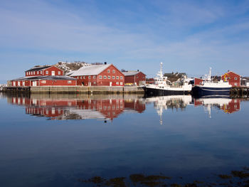 Reflection of houses in lake against sky