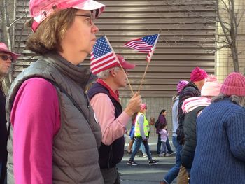 Rear view of people walking with flags in front of building